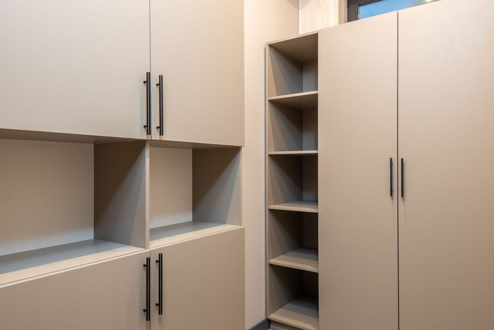 Großer beiger Kleiderschrank mit leeren Fächern im Zimmer